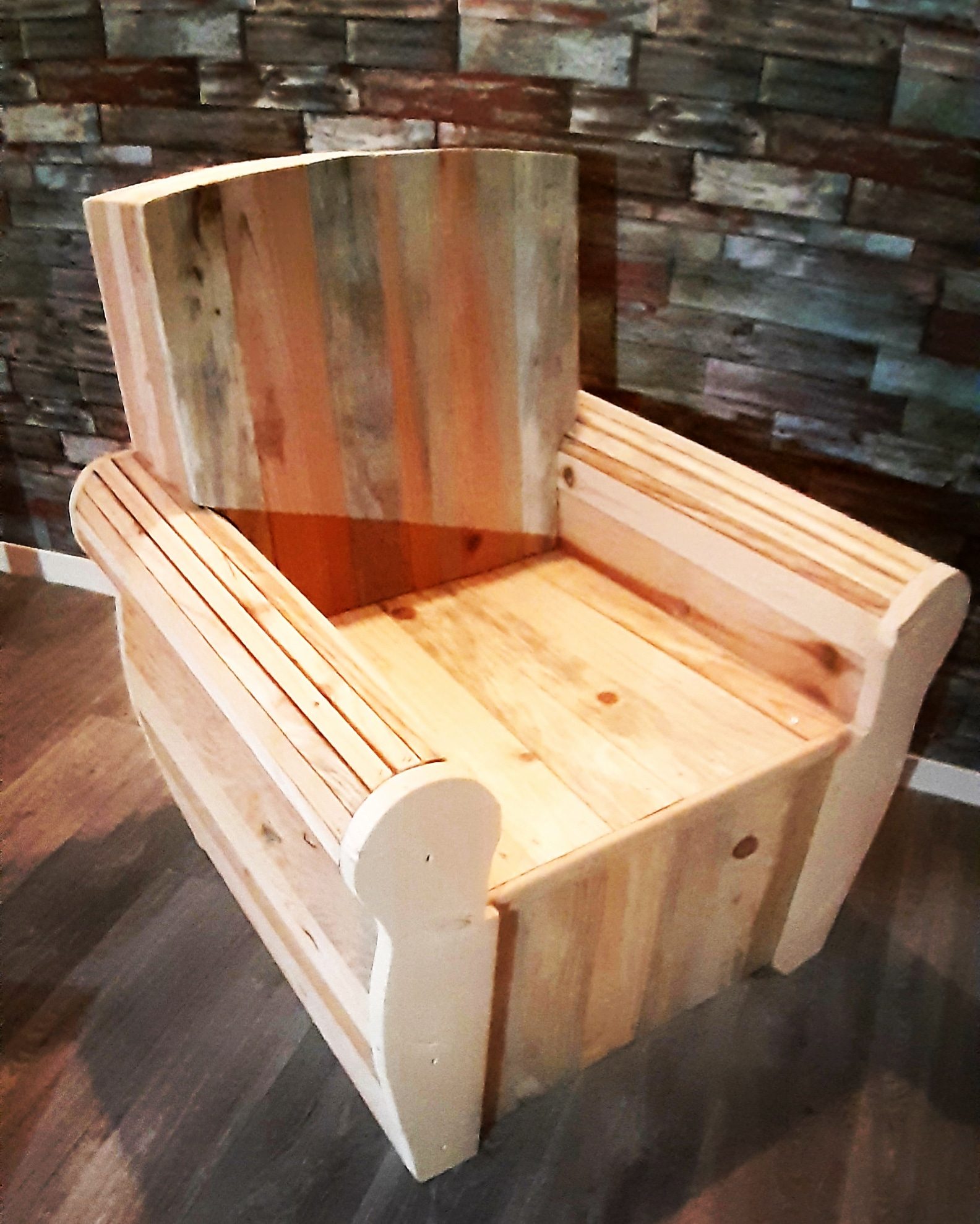 Fauteuil en bois de récupération devant un mur de pierre