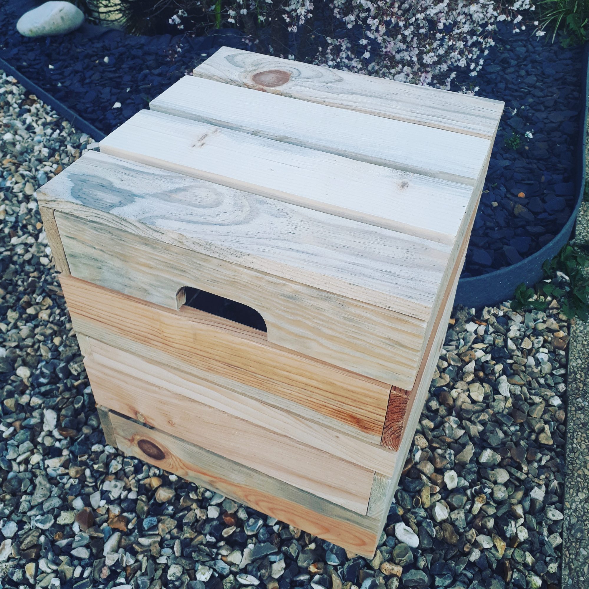 Pièce finie en bois de récupération, posée au jardin sous un cerisier en fleurs