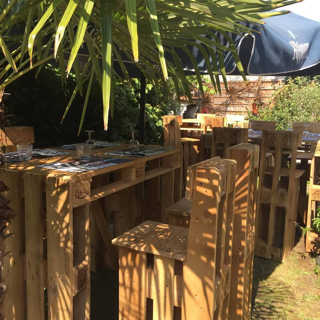 Terrasse de bar en palettes EPAL sous un palmier, en plein soleil