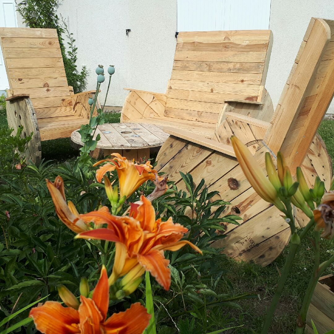 Salon de jardin Adirondack en bois de palette, parmi les lys en fleurs